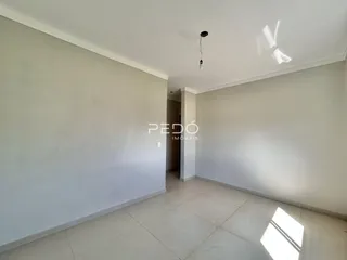 Um corredor interno com paredes brancas e piso de cerâmica.