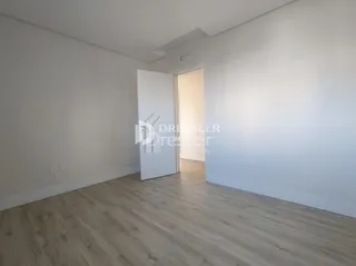 Interior de um cômodo com piso de madeira clara e paredes brancas.