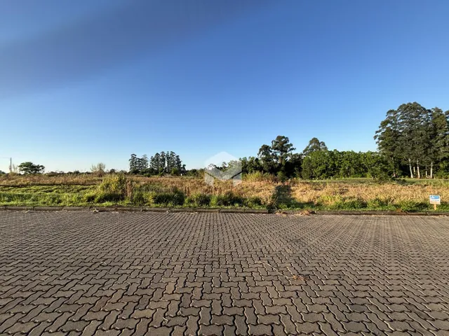 Vista da propriedade com área pavimentada e vegetação ao fundo.