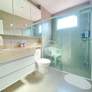 Foto de um banheiro com box de vidro e bancada de mármore.