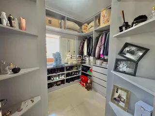 Interior de um corredor com estantes brancas e roupas penduradas.