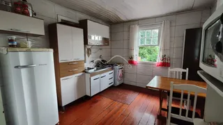 Foto interna de uma cozinha com armários brancos e piso de madeira.