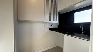 Foto de uma cozinha moderna com armários brancos e bancada escura.