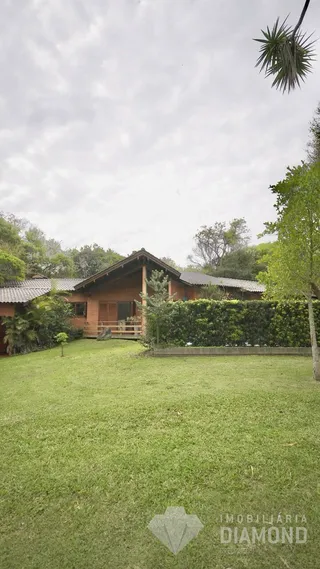 Vista externa de uma propriedade com gramado e vegetação ao fundo.