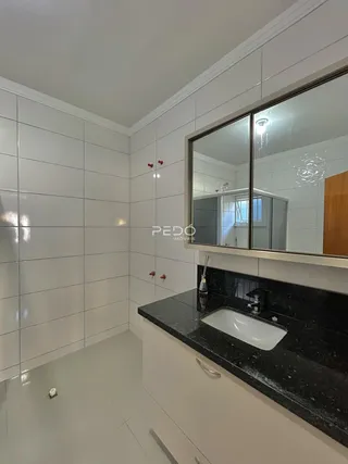 Banheiro com revestimento branco e bancada escura.