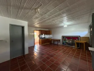 Interior de uma sala com piso de cerâmica vermelha e teto texturizado.