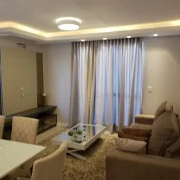 Sala de estar com cortinas claras e móveis escuros.