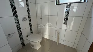 Foto de um banheiro com revestimento de azulejos brancos e um vaso sanitário.