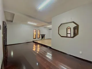 Uma sala ampla com piso de madeira escura e paredes brancas.
