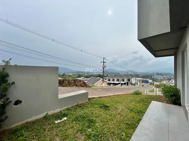 Vista externa de uma propriedade com gramado e muro.