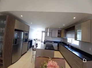 Ambiente interno de uma sala de estar com armários e bancadas de cozinha.