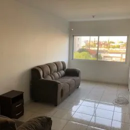 Sala de estar com um sofá escuro e uma grande janela mostrando a paisagem externa.