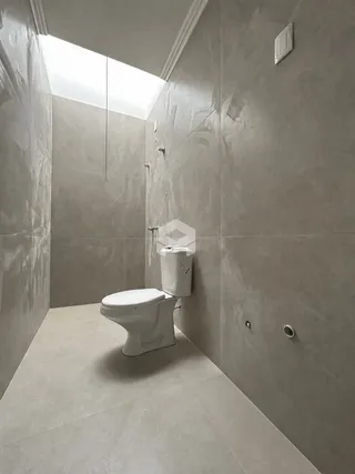 Foto de um banheiro com paredes e piso em tom de cinza claro.