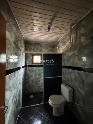 Foto interna de um banheiro com azulejos e piso escuro.
