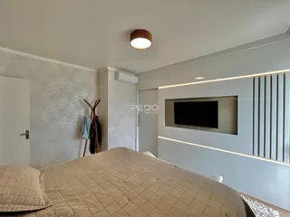 Quarto com cama grande e parede texturizada em um imóvel.