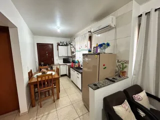 Foto interna de uma cozinha com armários brancos e bancadas.