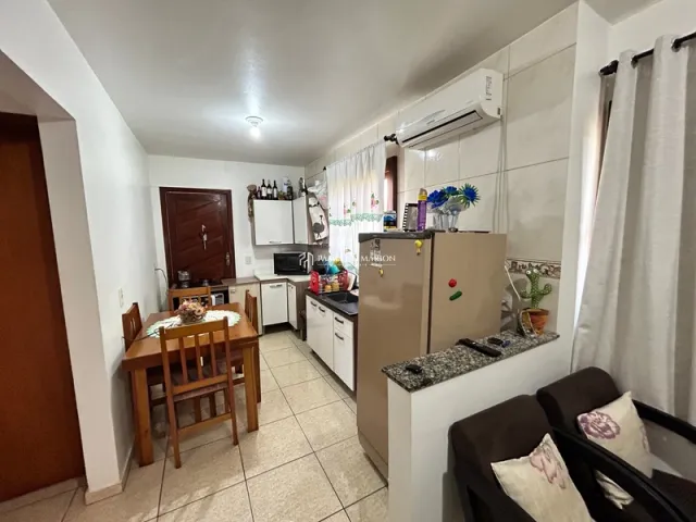 Foto interna de uma cozinha com armários brancos e bancadas.