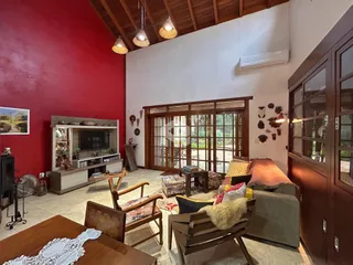 Sala de estar com paredes vermelhas e portas de vidro que dão acesso ao exterior.