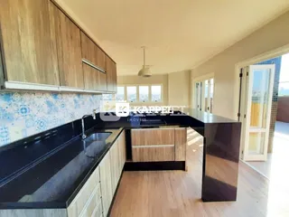 Cozinha moderna com armários de madeira e ilha escura.