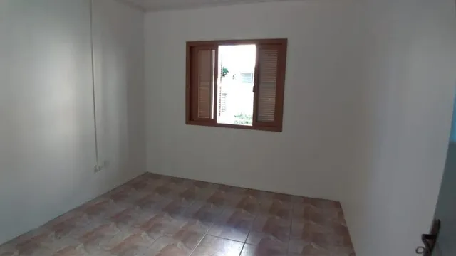 Foto de um cômodo interno com piso de madeira e uma janela.
