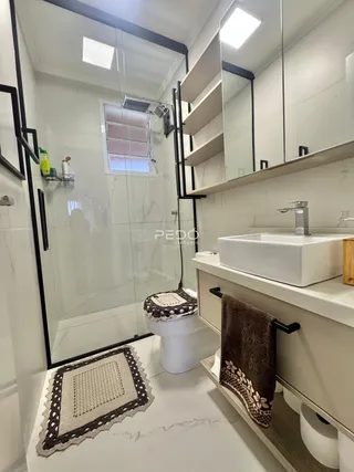 Banheiro moderno com box de vidro e revestimento em mármore claro.