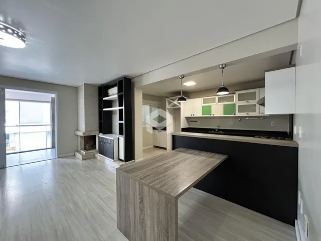 Ambiente interno de uma sala de estar com cozinha integrada e piso de madeira clara.