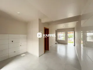 Sala de estar ampla com piso claro e paredes brancas.