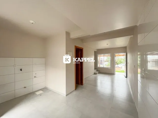 Sala de estar ampla com piso claro e paredes brancas.