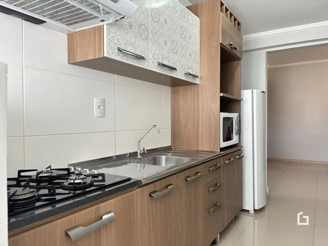 Cozinha moderna com armários de madeira e revestimento branco.