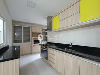 Foto de uma cozinha moderna com armários de madeira clara e bancadas escuras.