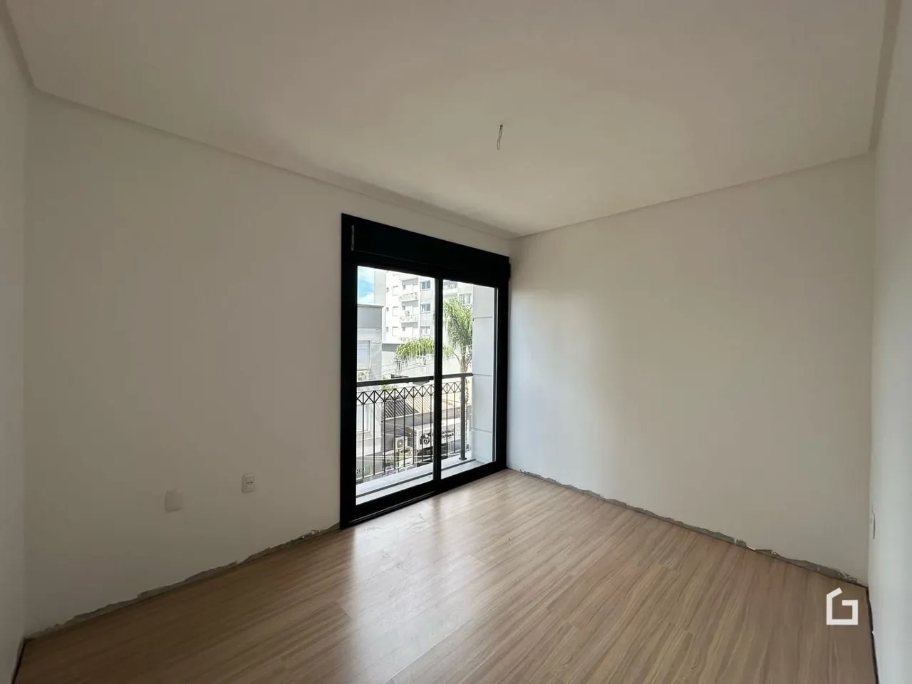 Ambiente interno de uma sala com piso de madeira e porta de vidro.