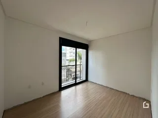 Ambiente interno de uma sala com piso de madeira e porta de vidro.