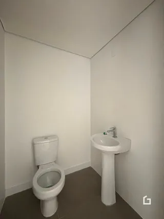Foto de um banheiro com vaso sanitário e pia brancos.