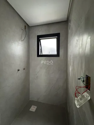 Foto de um corredor interno com paredes cinzentas e uma janela.