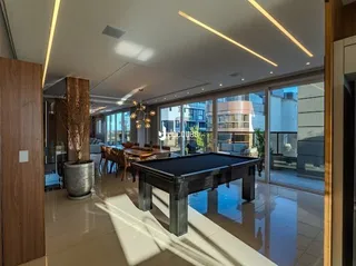 Sala de estar com mesa de bilhar e grandes janelas.