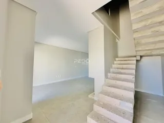 Vista de um corredor interno com escadaria em uma residência.