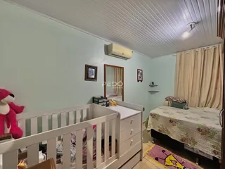 Quarto com cama e berço em ambiente claro.