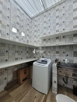 Imagem de uma cozinha com revestimento de azulejos e armários brancos.