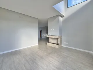 Vista interna de um espaço com piso de madeira clara e paredes brancas.