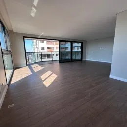 Sala de estar ampla com piso de madeira e grandes janelas.