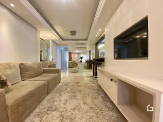 Sala de estar com sofá e televisão montada na parede.