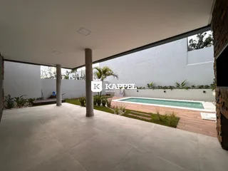 Vista da área externa com piscina e paisagismo.