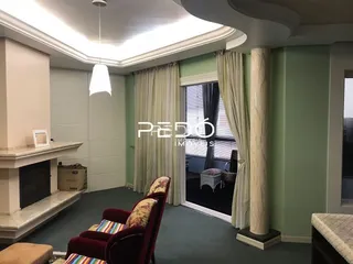 Sala de estar com teto alto e grandes janelas em um imóvel no Brasil.