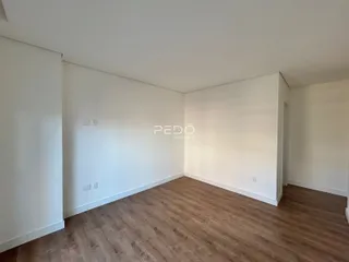 Ambiente interno de uma sala com piso de madeira clara.