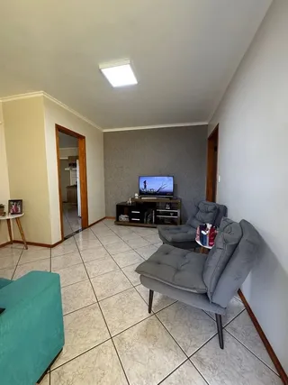 Sala de estar com sofá e televisão instalada.