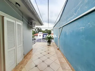 Foto de um corredor externo com piso de azulejos claros entre duas paredes de uma residência.
