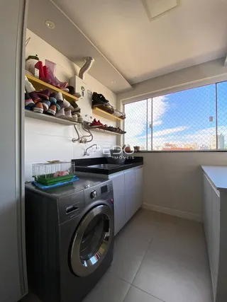 Foto de uma área de cozinha com máquina de lavar roupa e prateleiras em um imóvel.