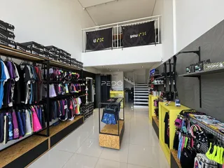 Vista interna de um espaço com estantes de roupas e um corredor.