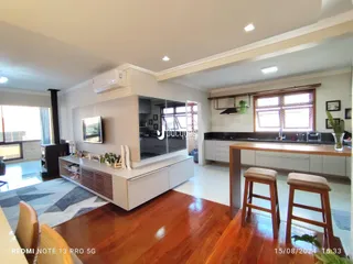 Sala de estar com cozinha integrada e piso de madeira em um imóvel no Lajeado.