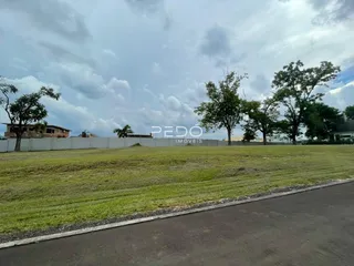 Vista de um terreno gramado com árvores ao fundo.